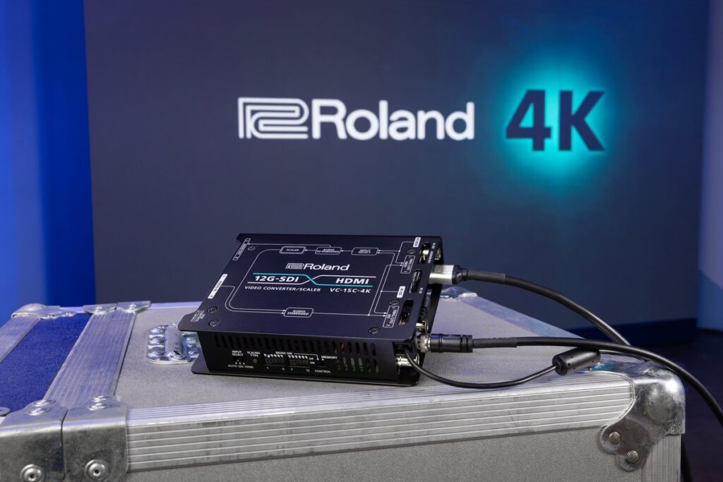 銀色の機材ケース上に置かれたRoland VC-1SC-4Kと、背景のRoland 4Kロゴ